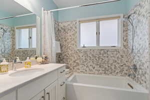 Bathroom featuring vanity, a healthy amount of sunlight, and shower / tub combo with curtain