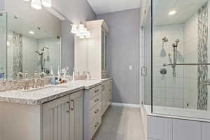 Bathroom with tile patterned floors, vanity, and a shower with door