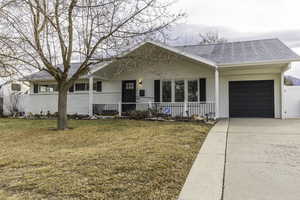 Ranch-style home with a porch, a garage, and a front lawn