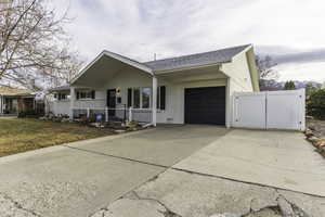 Ranch-style home featuring a porch, a garage, and a front lawn