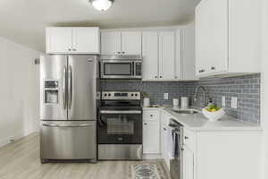 Kitchen with white cabinetry, sink, and stainless steel appliances