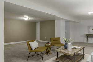 Living area featuring light carpet and a textured ceiling