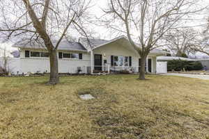 Single story home featuring a porch, a garage, and a front lawn