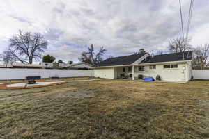 Back of property with a lawn, a patio, and an outdoor fire pit