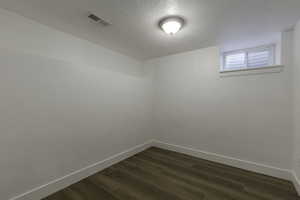 Unfurnished room featuring dark wood-type flooring and a textured ceiling