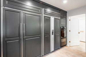 Kitchen with paneled refrigerator, double oven, and light hardwood / wood-style flooring