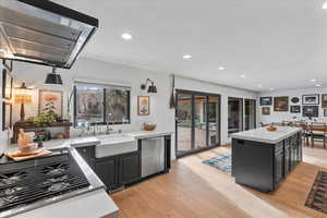 Kitchen featuring a center island, sink, stainless steel dishwasher, and light hardwood / wood-style flooring