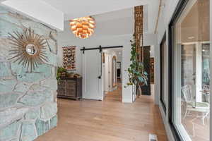 Hall with a barn door and light hardwood / wood-style floors