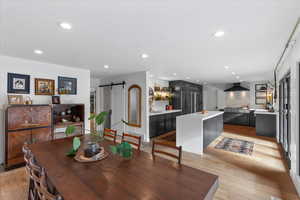 Dining room with sink, light hardwood / wood-style floors, and a barn door