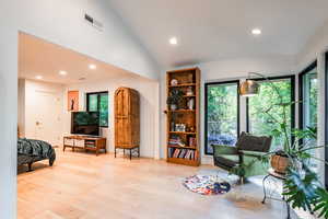 Sitting room featuring a healthy amount of sunlight, lofted ceiling, and light wood-type flooring