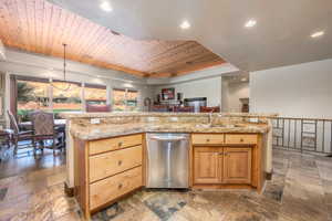 Kitchen featuring stainless steel dishwasher, an island with sink, sink, and wooden ceiling