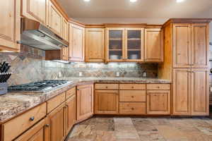 Kitchen featuring tasteful backsplash, light stone countertops, and stainless steel gas cooktop