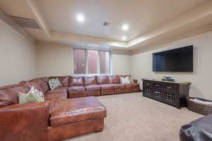 Living room featuring a tray ceiling and carpet