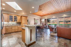 Kitchen with a kitchen island with sink, a breakfast bar area, wood ceiling, and a skylight