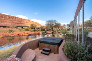 View of patio / terrace featuring a water and mountain view and a hot tub