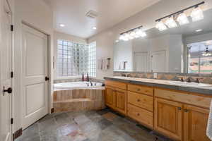 Bathroom featuring plenty of natural light, tiled bath, and vanity