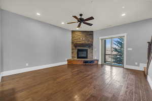 Unfurnished living room with hardwood / wood-style flooring, ceiling fan, and a fireplace