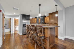 Kitchen featuring a kitchen island, appliances with stainless steel finishes, decorative light fixtures, a kitchen breakfast bar, and decorative backsplash