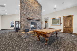 Playroom featuring pool table, a towering ceiling, carpet flooring, and a stone fireplace