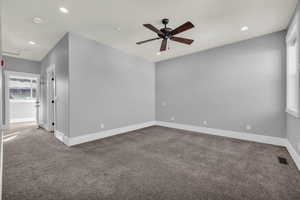 Carpeted empty room featuring ceiling fan