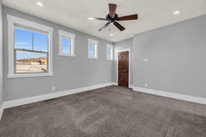 Empty room with dark colored carpet and ceiling fan