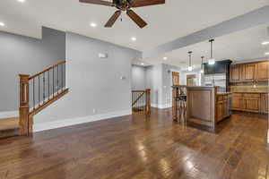 Kitchen with a kitchen island with sink, hanging light fixtures, a kitchen breakfast bar, dark hardwood / wood-style flooring, and stainless steel fridge with ice dispenser