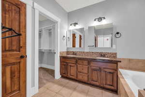 Bathroom featuring vanity, tile patterned floors, and tiled bath