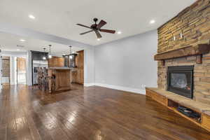 Unfurnished living room with a fireplace, dark hardwood / wood-style floors, and ceiling fan