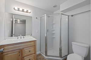 Bathroom with vanity, a shower with door, and toilet