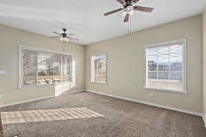 Empty room with ceiling fan and light colored carpet