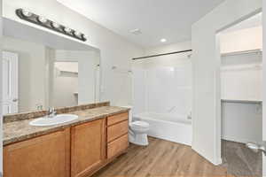 Full bathroom featuring wood-type flooring, vanity, washtub / shower combination, and toilet