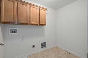 Clothes washing area with cabinets, hookup for an electric dryer, and hookup for a washing machine