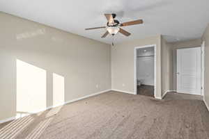 Unfurnished bedroom featuring ceiling fan, ensuite bathroom, and carpet floors