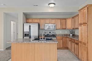 Kitchen featuring stainless steel appliances, sink, a center island with sink, and light tile patterned floors