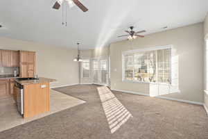 Kitchen featuring pendant lighting, sink, light colored carpet, a center island with sink, and stainless steel dishwasher