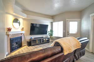 Living room with a tiled fireplace and light hardwood / wood-style flooring