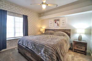 Bedroom featuring brick wall, carpet flooring, and ceiling fan