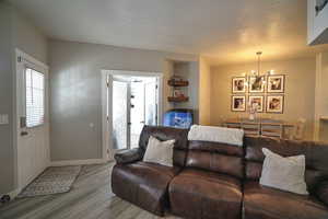 Living room featuring a textured ceiling, a chandelier, a fireplace, and light wood-type flooring