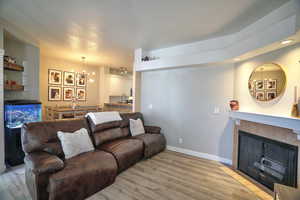 Living room featuring sink, an inviting chandelier, a fireplace, and light hardwood / wood-style flooring