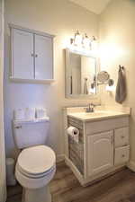 Bathroom with hardwood / wood-style flooring, vanity, and toilet