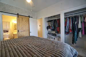 Bedroom with multiple closets, connected bathroom, and a barn door