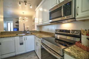 Kitchen with white cabinetry, appliances with stainless steel finishes, sink, and kitchen peninsula