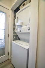 Laundry area with light hardwood / wood-style flooring and stacked washer and clothes dryer