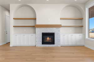 Unfurnished living room featuring a brick fireplace, light hardwood / wood-style flooring, and built in features