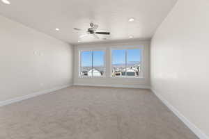 Carpeted spare room with ceiling fan and a textured ceiling