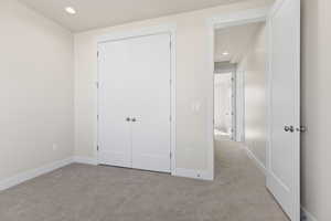 Unfurnished bedroom featuring light carpet and a closet