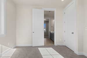 Unfurnished bedroom featuring ensuite bathroom and light carpet