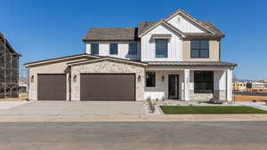 Modern farmhouse featuring stone siding, driveway, and board and batten siding