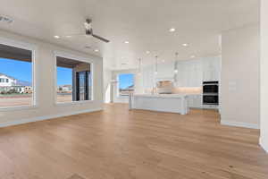 Unfurnished living room featuring ceiling fan, sink, and light hardwood / wood-style flooring