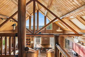 Interior space featuring wooden ceiling, rail lighting, beam ceiling, and a notable chandelier